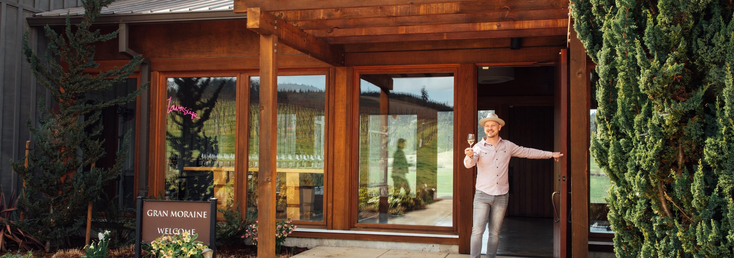 Man standing outside Gran Moraine tasting room holding a glass of white wine