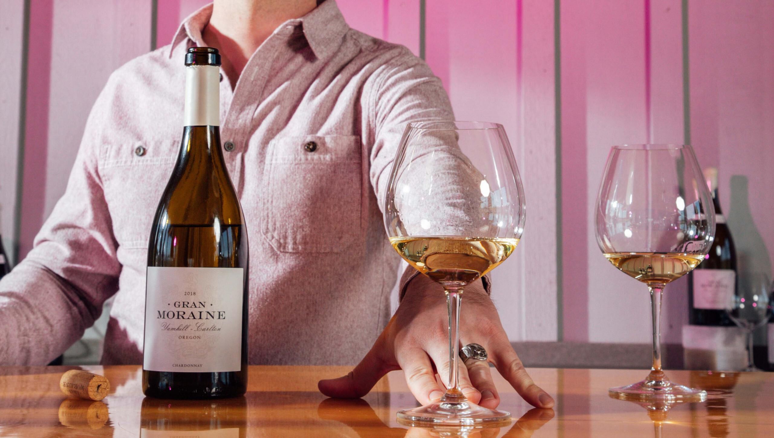 Man serving white wine behind a wine tasting bar