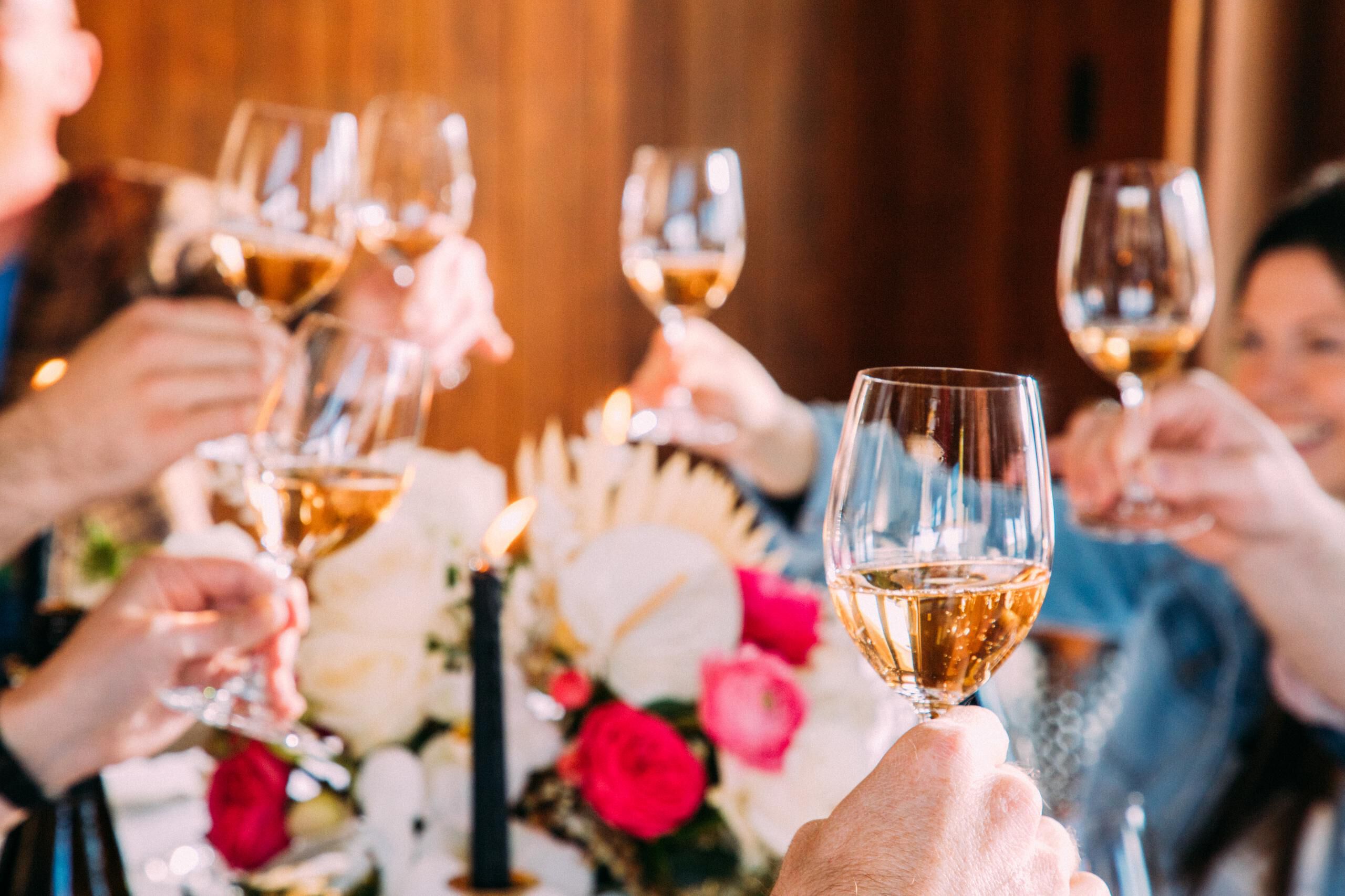 Several people holding up glasses of Rosé around a table