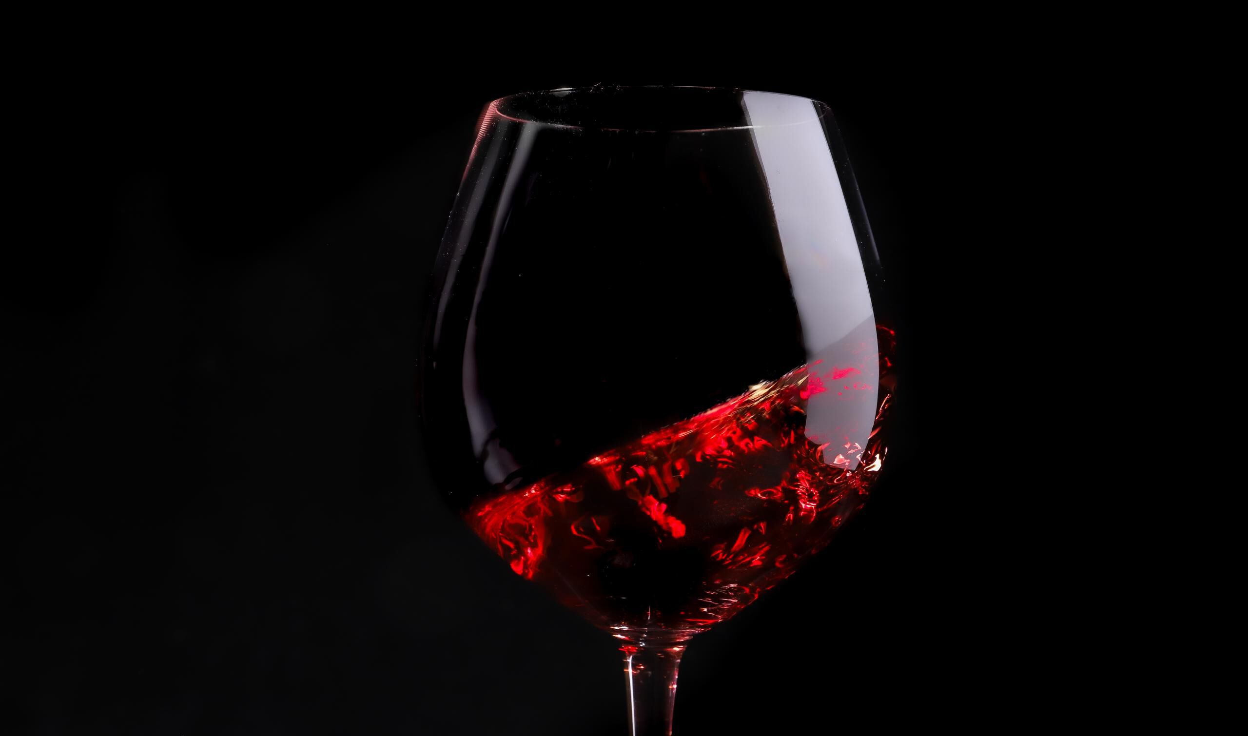 Pinot Noir swirling in a glass against a black background